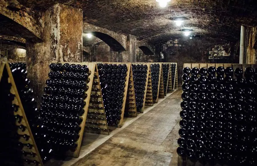 Botellas reposando en pupitres dentro de una bodega subterránea
