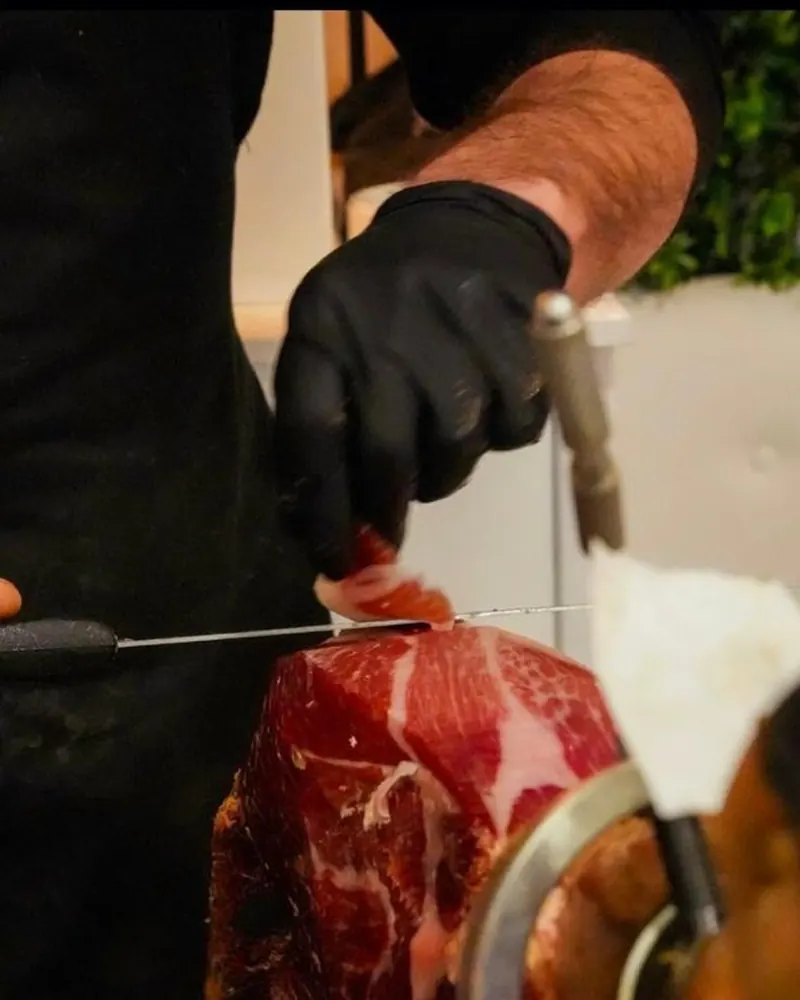 Cortador con guante preparando una pieza ibérica